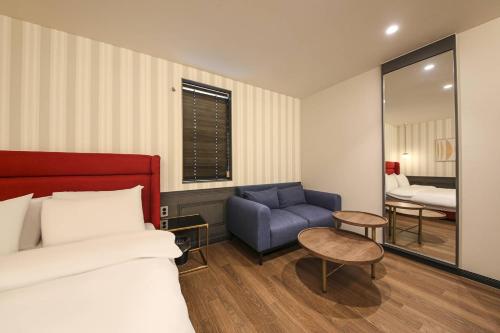 a bedroom with a bed and a blue chair at Browndot Hotel Deokjin in Jeonju