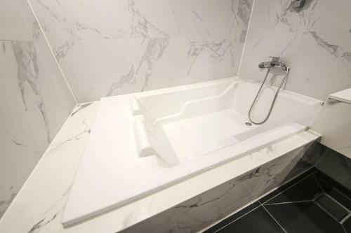a white bath tub in a bathroom with marble walls at Browndot Hotel Deokjin in Jeonju