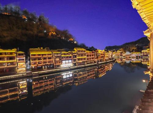 a group of houses on a river at night at Fenghuang Ancient Town Lazy Cat Riverside Inn in Fenghuang