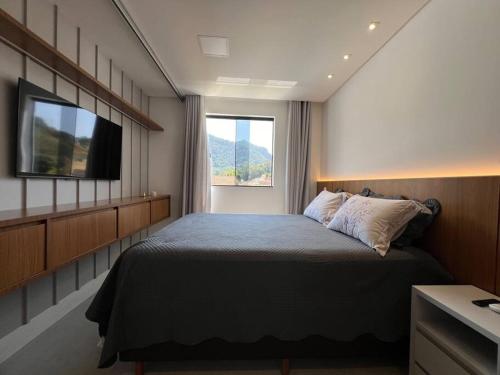 a bedroom with a large bed and a television at Apto lindo nas montanhas! in Venda Nova do Imigrante