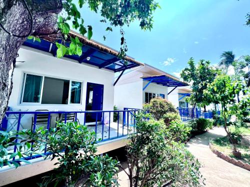 a white house with blue railing and trees at Three Trees Samui Resort - Sarocha Villa in Lamai