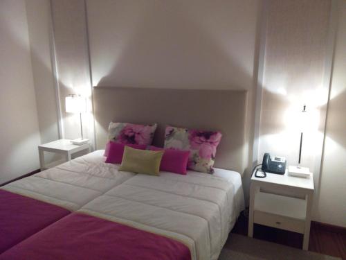a bedroom with a large bed with pink pillows at Monsanto GeoHotel Escola in Monsanto
