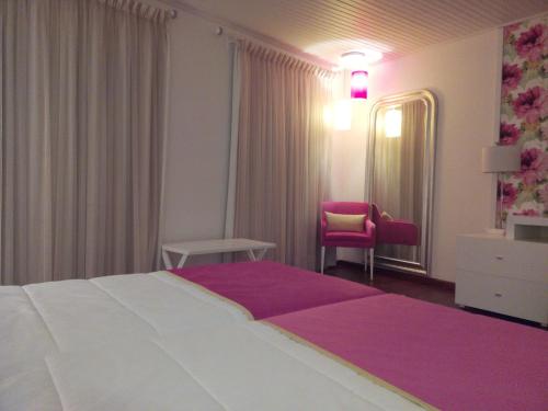 a hotel room with a large bed and a chair at Monsanto GeoHotel Escola in Monsanto