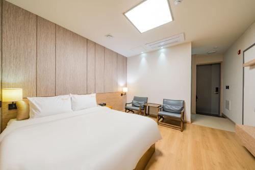 a hotel room with a bed and two chairs at Yeosu Stay Hotel in Yeosu