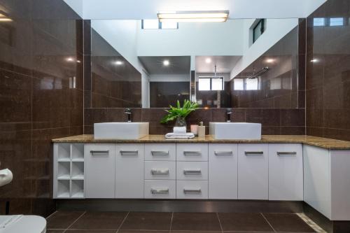 Un baño con dos lavabos y un espejo. en Airlie Nights, en Airlie Beach