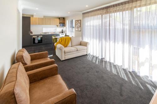 a living room with a couch and chairs and a kitchen at 2BR Townhouse, Riccarton Mall, Hagley Park in Christchurch