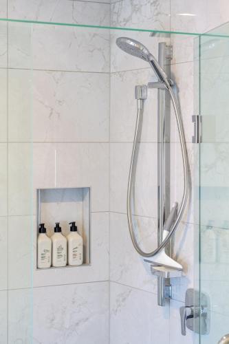 a shower with three bottles of soap in a bathroom at 2BR Townhouse, Riccarton Mall, Hagley Park in Christchurch