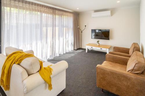 a living room with two couches and a tv at 2BR Townhouse, Riccarton Mall, Hagley Park in Christchurch