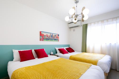 a bedroom with two beds with red and yellow sheets at M&P Osaka Hotel in Osaka
