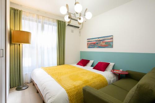 a bedroom with a bed and a couch and a window at M&P Osaka Hotel in Osaka