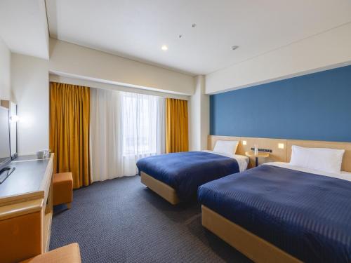 a hotel room with two beds and a television at Kansai Airport Washington Hotel in Izumi-Sano