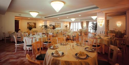 a banquet hall with tables and chairs with white tablecloths at Fattoria La Principina Hotel & Congress in Principina Terra