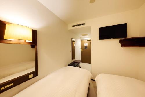 a hotel room with two beds and a television at Centurion Hotel Hamamatsu in Hamamatsu
