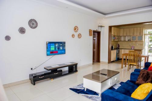 un salon avec un canapé bleu et une télévision dans l'établissement WOODLAND CENTER APARTMENTs, à Kigali