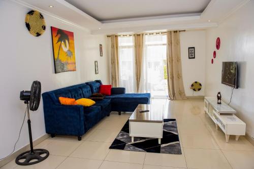 - un canapé bleu dans un salon blanc dans l'établissement WOODLAND CENTER APARTMENTs, à Kigali