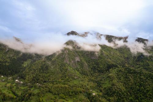 a mountain covered in mist and clouds next to a town at Guest House Sunrise in Khulo