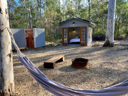a hammock in front of a small cabin in the woods at Casa Azul - Off-grid Hideaway Agnes Water 1770 in Agnes Water