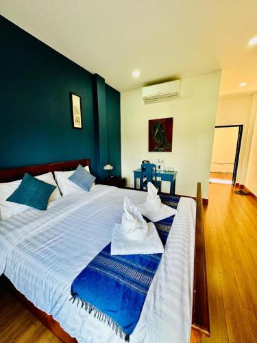 a bedroom with a large white bed with blue walls at Zen NamKhan Riverside in Luang Prabang