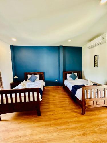 two beds in a room with blue walls and wooden floors at Zen NamKhan Riverside in Luang Prabang
