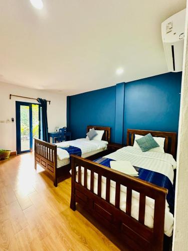 a bedroom with two beds and a blue wall at Zen NamKhan Riverside in Luang Prabang