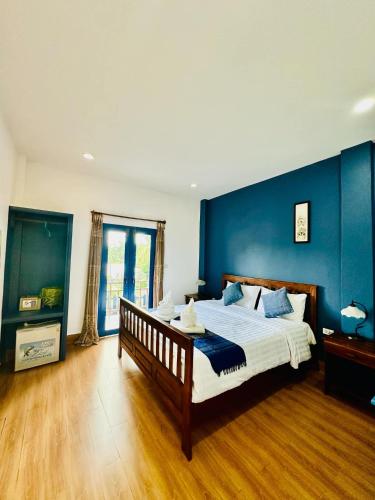 a bedroom with a large bed with a blue wall at Zen NamKhan Riverside in Luang Prabang