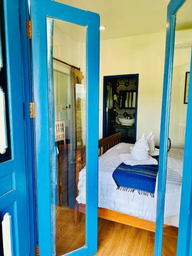 a blue door leading to a bedroom with a bed at Zen NamKhan Riverside in Luang Prabang