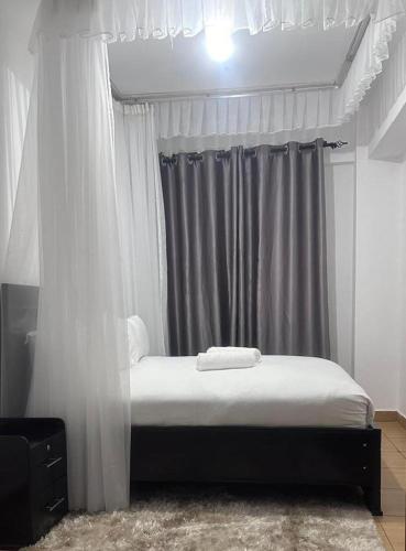 1 dormitorio con cama con dosel y cortinas en JB apartment, en Kisumu
