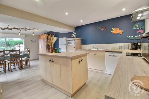 une grande cuisine aux murs bleus et une salle à manger dans l'établissement Ty beg hastel, à Plouha