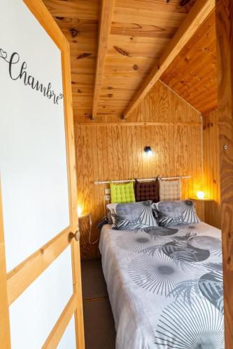 une chambre avec un lit dans une cabane en bois dans l'établissement Gîte Chalet des 2 M 2/4 personnes, à Antrenas