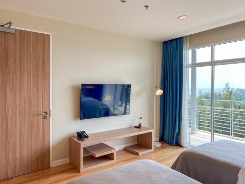 a bedroom with a television on a wall with a window at The Kaset, Hua Hin in Hua Hin