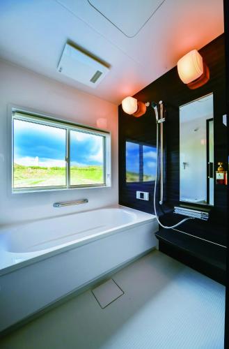 a bathroom with a bath tub and a window at GranVista角島 in Oyama