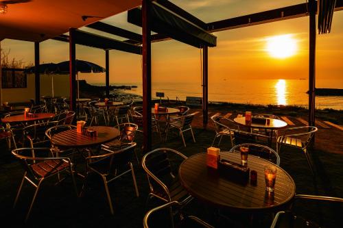 a restaurant with tables and chairs at the beach at sunset at GranVista角島 in Oyama