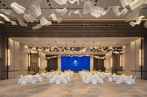a large banquet hall with white tables and chairs at Doubletree By Hilton Kaifeng in Kaifeng