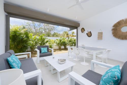 un salon avec des meubles blancs et une grande fenêtre dans l'établissement Pointe aux Canonniers Beach Luxury Apartment, à Pointe aux Cannoniers
