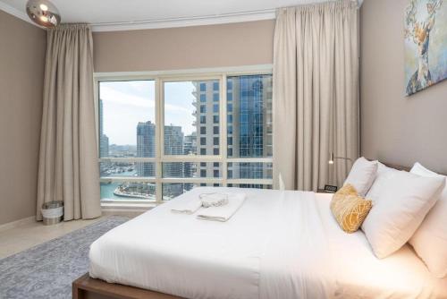 a bedroom with a large white bed with a large window at 2 Bedroom Apartment full Marina View in Dubai