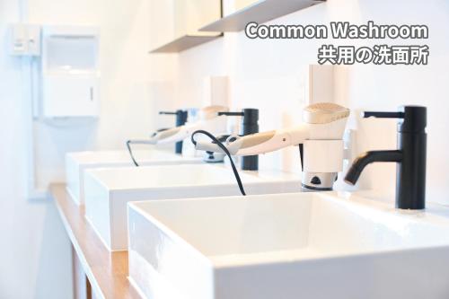 a row of white sinks in a bathroom at J-Hoppers Lake Biwa Guesthouse in Otsu