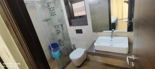 a bathroom with a sink and a toilet and a mirror at Telferk Acron Seawinds Apartment- Baga in Calangute