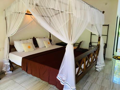 a bedroom with a canopy bed with white curtains at Soorya Guest Mirissa in Mirissa