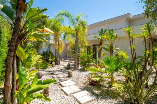un jardin avec des palmiers et des bancs devant un immeuble dans l'établissement REF 1941 - Cannes Center - Villa for rent, à Cannes
