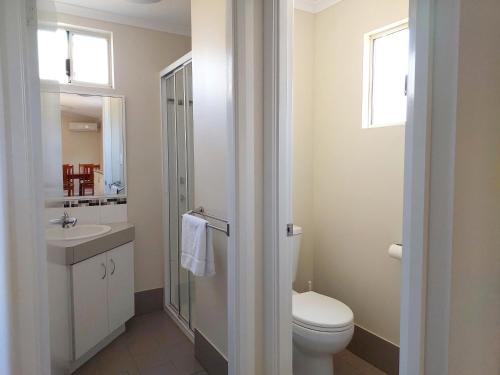 a white bathroom with a toilet and a sink at Mt Barker Holiday Park - Western Australia in Mount Barker
