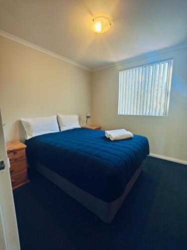 a bedroom with a blue bed and a window at Mt Barker Holiday Park - Western Australia in Mount Barker