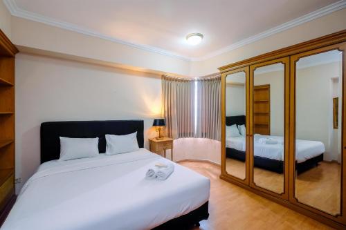 a hotel room with two beds and a mirror at Luxury 3BR Apartment at Sudirman Tower Condominium By Travelio in Jakarta