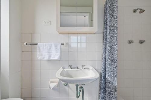 a white bathroom with a sink and a shower at Your Stylish Balmain Retreat in Sydney