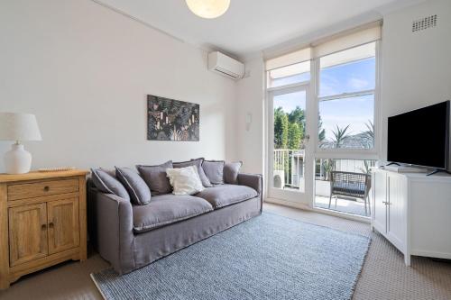 a living room with a couch and a flat screen tv at Your Stylish Balmain Retreat in Sydney