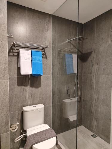 a bathroom with a toilet and a glass shower at True Blue Sanno Pluit - Jakarta in Jakarta