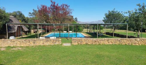 a house with a swimming pool and a stone wall at Riverbank in Tulbagh