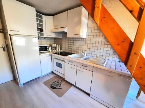 une cuisine avec des armoires blanches et un réfrigérateur blanc dans l'établissement Résidence Jetay - Appartement avec mezzanine pour 6 personnes MAE-4624, aux Menuires