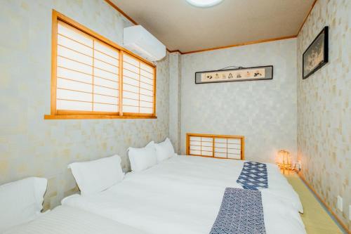 a bedroom with two white beds and a window at キャンペーン中交通便利難波から1駅大国町駅から徒歩5分4室2トイレ2シャワー室広い宿泊です in Osaka