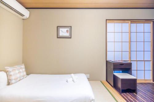 a bedroom with a bed and a desk and a window at Muji Arashiyama Villa 無時嵐1階2階賃貸し 駅まで徒歩2分 in Kyoto