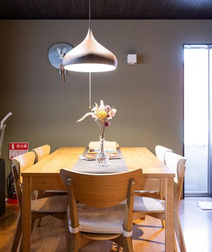 a dining room table with a vase of flowers on it at Muji Arashiyama Villa 無時嵐1階2階賃貸し 駅まで徒歩2分 in Kyoto